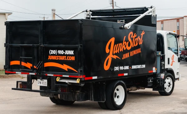 Rear view of a black JunkStart Junk Removal truck with orange branding and a white cab.