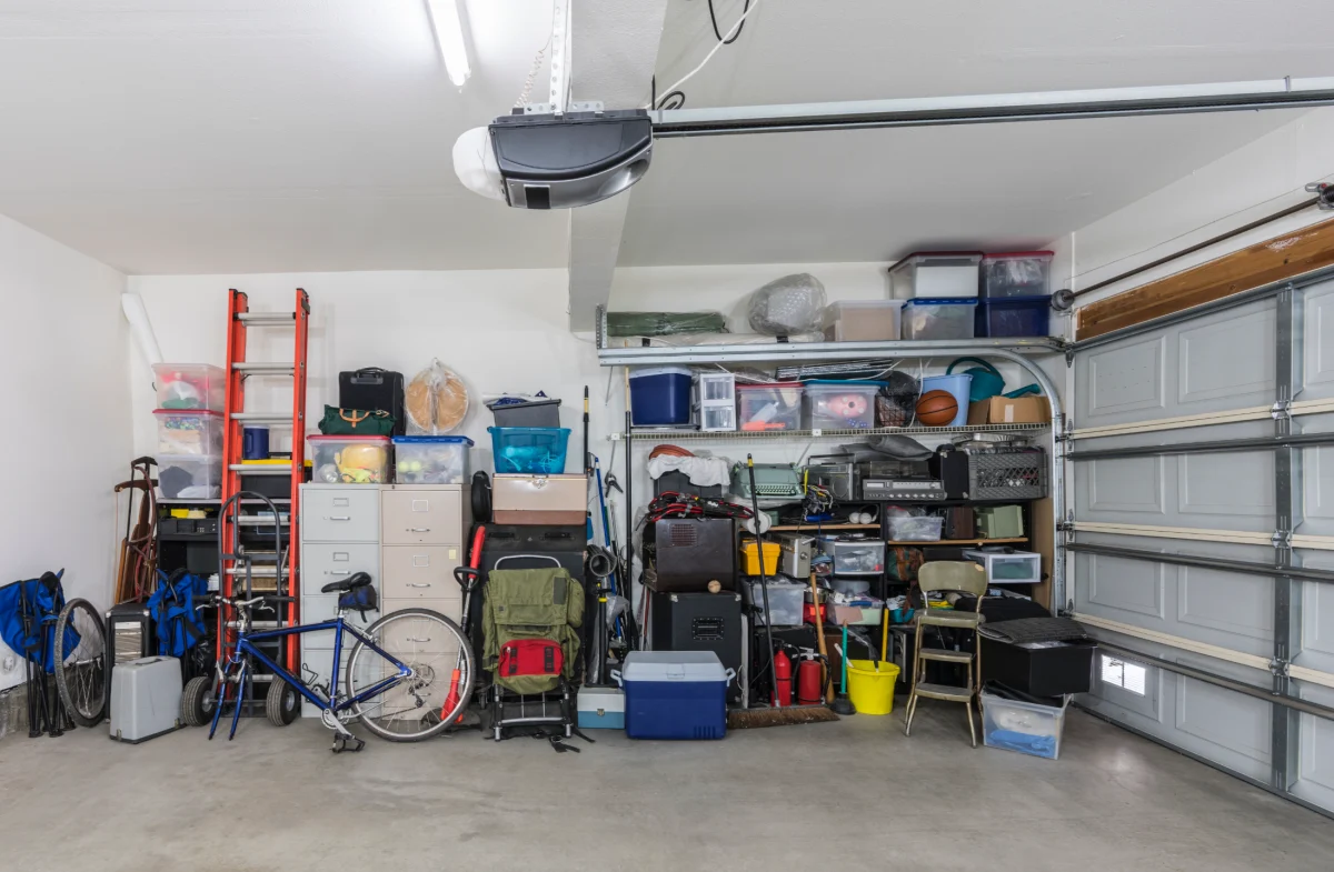 A busy garage interior packed with various household items, storage bins, and a bicycle